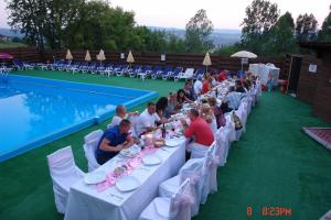 un gruppo di persone seduti ai tavoli accanto a una piscina di Hostel Restaurant Ciuperca a Hunedoara