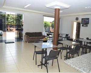 a restaurant with tables and chairs and a couch at Hotel Cardoso in Quirinópolis
