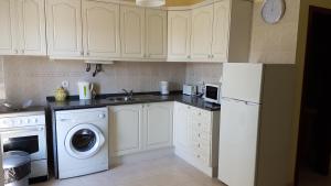 a kitchen with white cabinets and a washer and dryer at Villa Mucifal A in Sintra