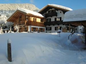 un edificio cubierto de nieve con un patio cubierto de nieve en Gästehaus Annemarie, en Reit im Winkl