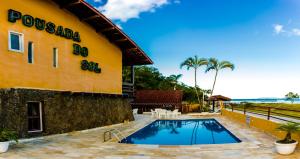 a resort with a swimming pool in front of a building at Hotel Pousada do Sol in Ubatuba