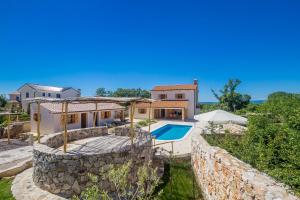 a villa with a swimming pool and a stone wall at Holiday house Hojevica - Kras, Krk in Kras