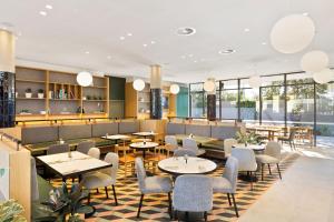 um restaurante com mesas, cadeiras e janelas em Mantra Hotel at Sydney Airport em Sydney