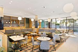 a restaurant with tables and chairs and windows at Mantra on Sydney Airport in Sydney