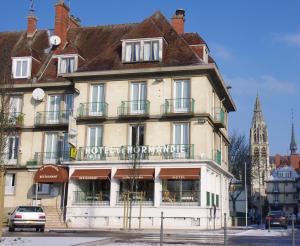 un grand bâtiment dans une ville avec une tour de l'horloge dans l'établissement Logis Le Normandie, à Caudebec-en-Caux