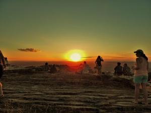 un grupo de personas de pie en una colina viendo la puesta de sol en Casas Label - Hospedagem São Thomé, en São Thomé das Letras
