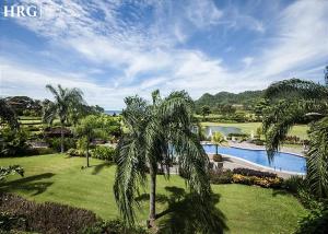 a resort with a swimming pool and palm trees at Ocean View Condo in Los Sueños in Herradura