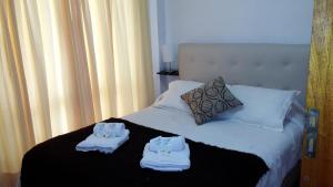1 dormitorio con 1 cama con toallas en Departamentos El Ceibo II en Mendoza