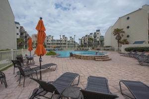 a swimming pool with chairs and umbrellas in a resort at South Padre Island Beach Rentals in South Padre Island