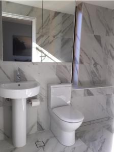 a white bathroom with a toilet and a sink at The KC Elizabeth Bay in Sydney