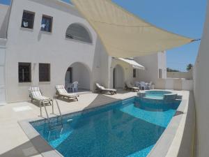 a swimming pool with chairs and a house at Residence Djerba in Midoun