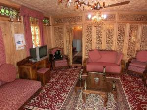 a living room with pink furniture and a tv at Chicago Group of Houseboats in Srinagar