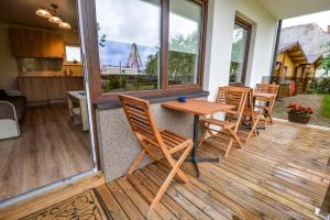 a porch with a wooden table and chairs on a deck at Vila Tante in Šventoji