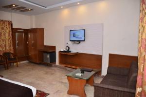 a hotel room with a couch and a tv on the wall at Hotel Basera Brij Bhoomi Vrindavan in Vrindāvan
