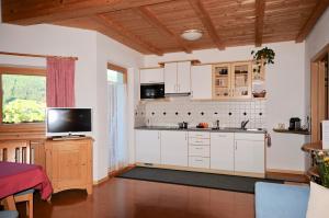 cocina con armarios blancos y TV de pantalla plana en Apartments Dolina, en Ortisei