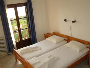 two twin beds in a room with a window at Hotel Tsagarada in Tsagarada