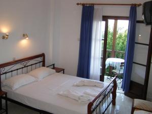a bedroom with a bed with blue curtains and a balcony at Hotel Tsagarada in Tsagarada