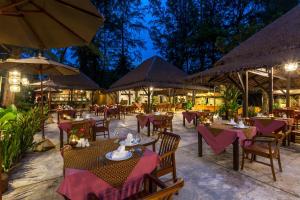 un restaurante al aire libre con mesas, sillas y sombrillas en Haadson Resort - Khaolak, Phangnga, en Khao Lak