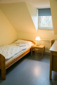 ein kleines Schlafzimmer mit einem Bett und einem Fenster in der Unterkunft Jugendhaus St. Kilian in Miltenberg