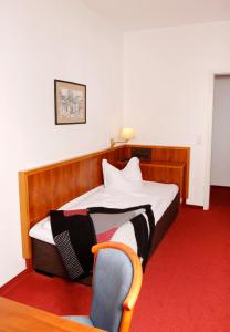 a hotel room with a bed and a chair at Brocki's Hotel Stadt Hamburg in Parchim