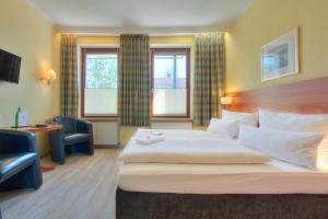ein Hotelzimmer mit einem Bett, einem Schreibtisch und 2 Fenstern in der Unterkunft Hotel Morgensonne garni in Büsum