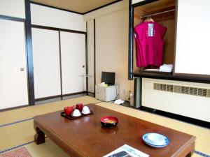 a living room with a table and a pink shirt on a shelf at Hotel Manyotei in Nikko