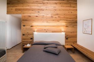 1 dormitorio con 1 cama con pared de madera en Hotel Ferrovia en Calalzo