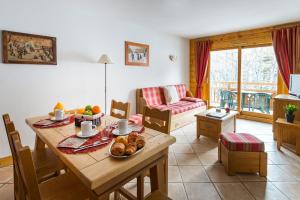 una sala de estar con una mesa con comida. en travelski home premium - Résidence Le Hameau du Rocher Blanc 4 stars en Saint-Chaffrey