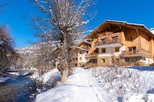 サン・シャフレにあるtravelski home premium - Résidence Le Hameau du Rocher Blanc 4 starsの川の横の雪の丸太小屋