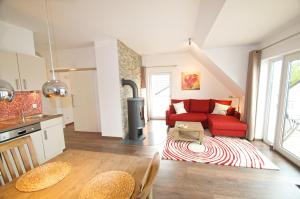 a kitchen and a living room with a red couch at mönchgut living & spa in Gager