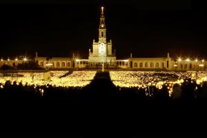 a large building with a clock tower at night at Hotel Cruz Alta in Fátima +4 photos