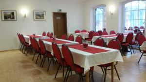 a conference room with tables and red chairs at Hotel-Garni Herzog in Loher Ostmark