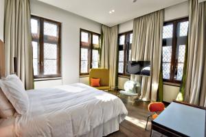 a bedroom with a bed and a desk and windows at The Fourth - Tafelrond in Leuven