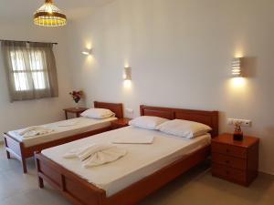 2 Einzelbetten in einem Zimmer mit 2 Tischen in der Unterkunft Atlantida Hotel in Koufonisia