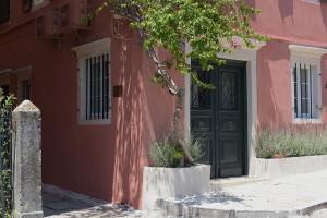a pink house with a green door and a tree at Durrell Liston Suites in Corfu Town +8 photos