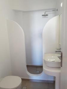 a white bathroom with a toilet and a sink at Atlantida Hotel in Koufonisia +50 photos