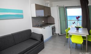 a living room with a couch and a table and a kitchen at Residence Acquasuite in Martinsicuro
