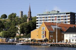 a large yellow building next to a building next to the water at Thon Hotel Tønsberg Brygge in Tønsberg