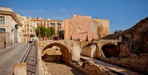 an old stone bridge in a city with buildings at Plaça De La Font in Tarragona