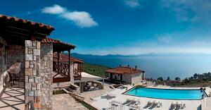 a house with a swimming pool in front of the water at Karavia Lux Inn in Afissos