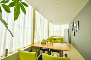 a dining room with a table and green chairs at Jinjiang Inn Haikou Binhai Avenue Qilou Old Street in Haikou