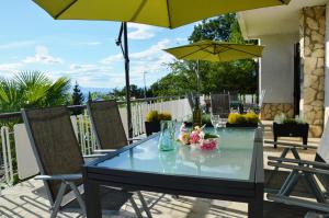 a glass table with flowers and a yellow umbrella at Apartments Martina in Njivice