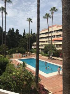 una piscina con palmeras y un edificio en Parque Marbella, en Marbella