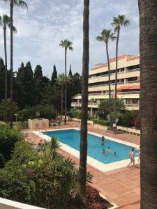 a swimming pool with palm trees and a building at Parque Marbella in Marbella