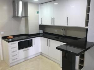 cocina con armarios blancos y encimera negra en Parque Marbella, en Marbella