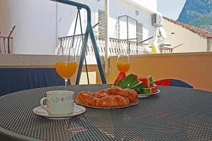 einen Tisch mit zwei Gläsern Orangensaft und einem Teller Essen in der Unterkunft Apartment Tomislav in Zaostrog