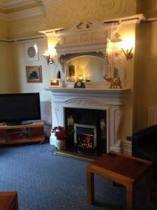 a living room with a fireplace and a tv at Rostrevor Hotel - Guest House in Bury