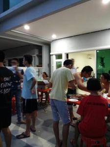 a group of people standing in a kitchen preparing food at Pangkor Holiday Home in Pangkor
