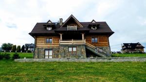 a wooden house with a gambrel roof on a field at Dom Pod Bachledówką in Czerwienne