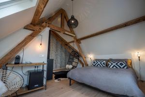 een slaapkamer met een bed in een kamer met houten balken bij Loods Logement in Oost-Vlieland